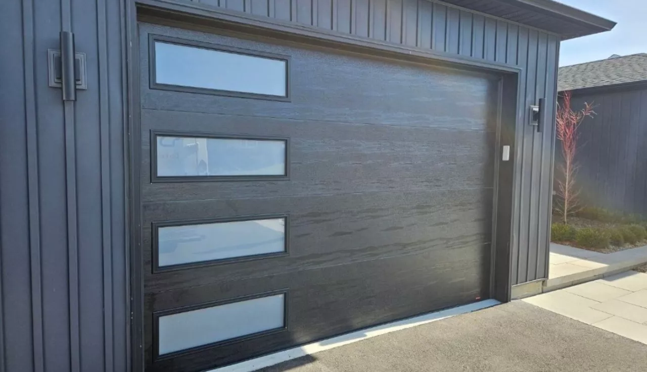 Black garage door with windows, offering a modern and sleek design.
